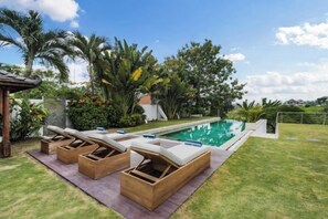 Une piscine avec des chaises longues et une pergola.