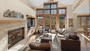 A spacious living room with a fireplace, large windows, and a high ceiling. - 223cdk-3 (Keystone)