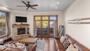 A spacious living room with a fireplace, leather sofas, a flat-screen TV, and a ski rack on the wall. - Wm102cf-2 (Frisco)