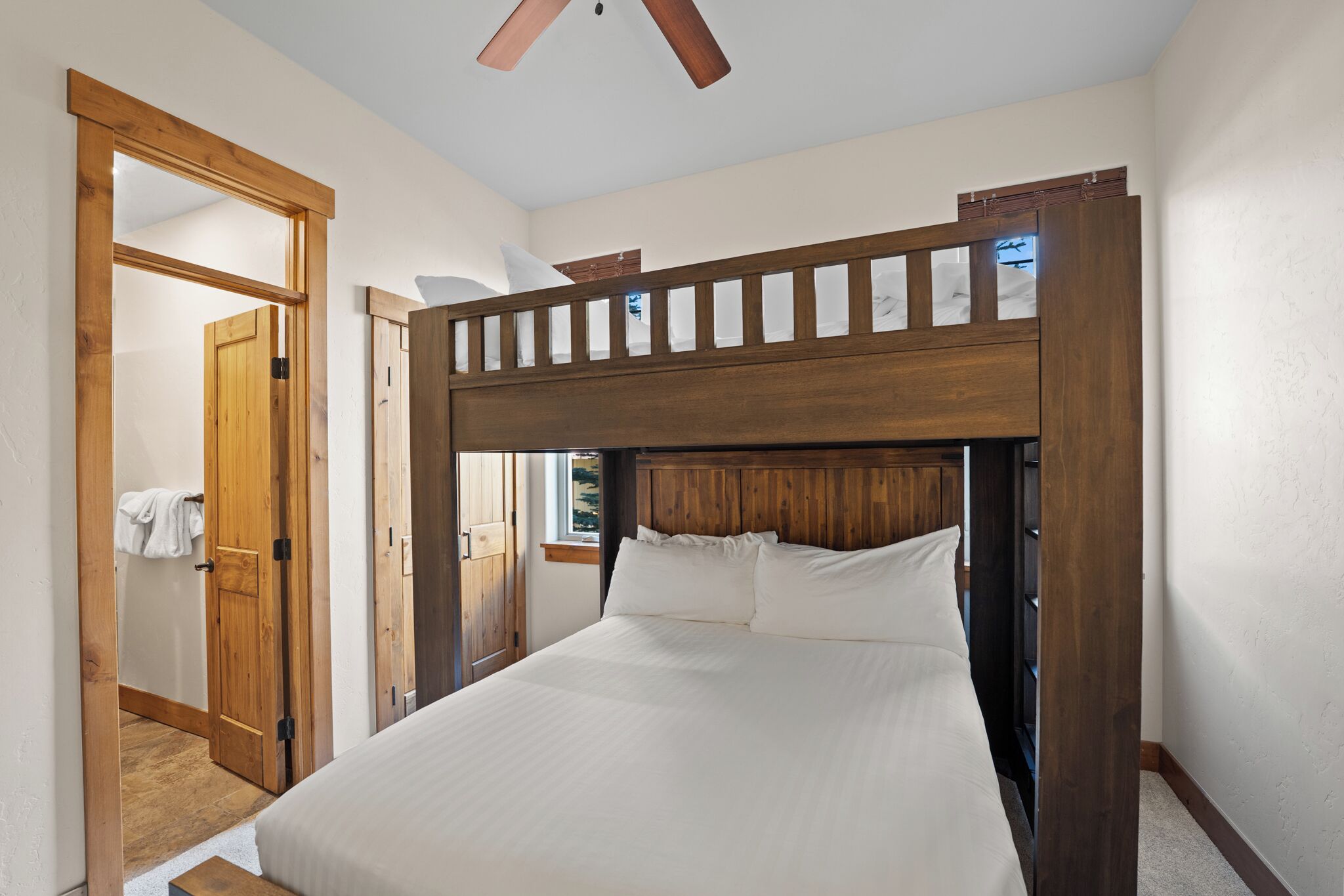 A bedroom with a wooden headboard, a large bed, and a wooden door leading to another room.