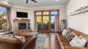 A living room with a fireplace, leather sofas, a flat-screen TV, and a ceiling fan. - Wm102cf-2 (Frisco)