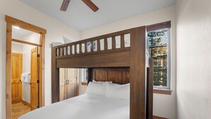 A bedroom with a wooden bunk bed, a wooden wardrobe, and a window with a view of trees. - Wm102cf-2 (Frisco)