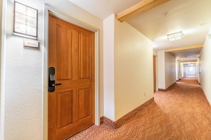 A hallway with a wooden door, a number plate, and a patterned carpet. - Gateway #5028 (Keystone)