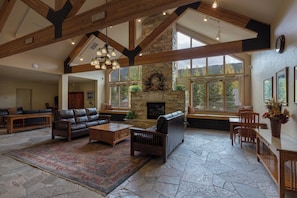 A spacious living room with a stone fireplace, wooden furniture, and large windows. - Gateway #5028 (Keystone)