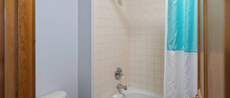 A bathroom with a shower, toilet, and bathtub.