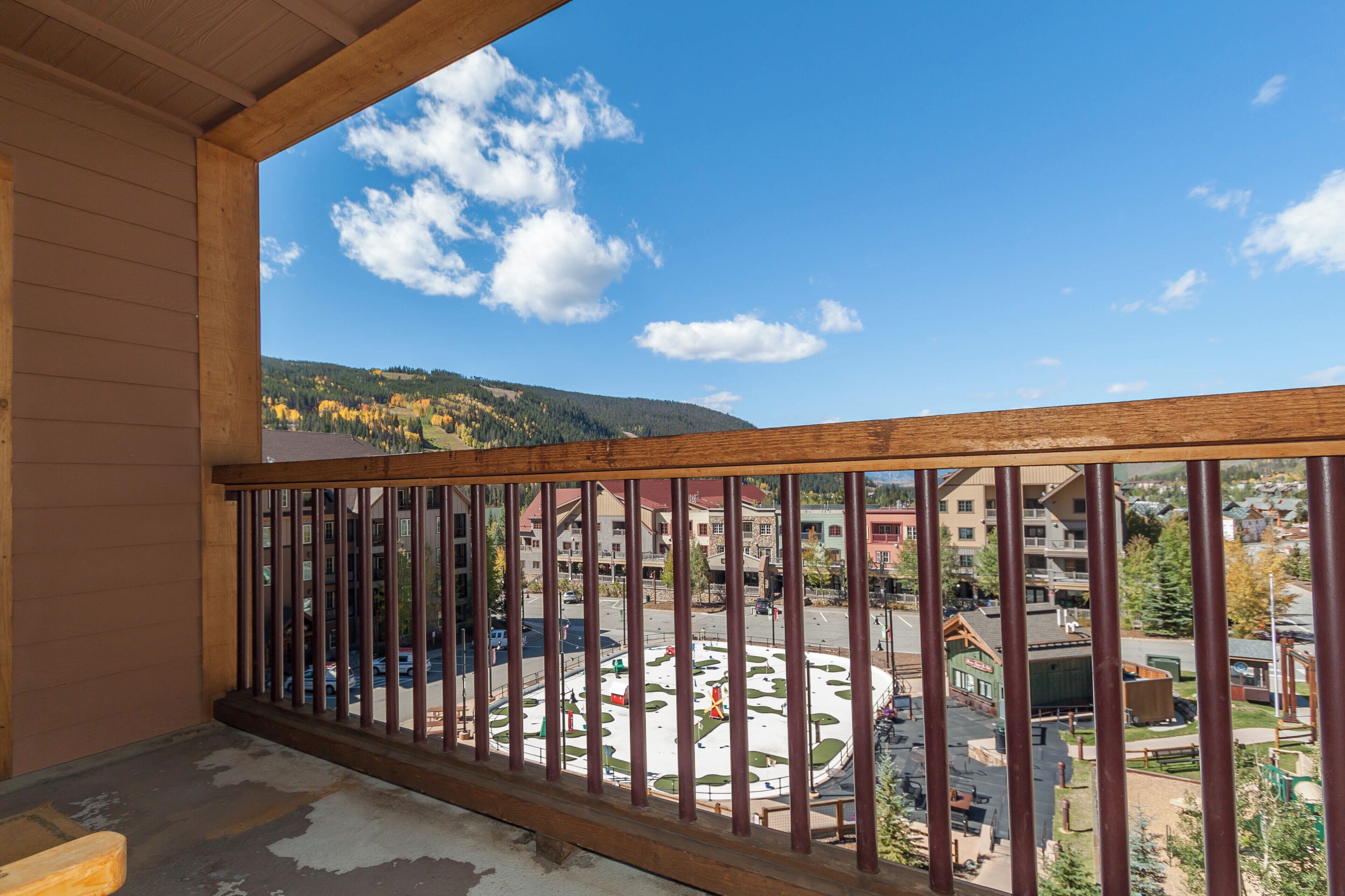 A balcony with a view of a town square, buildings, and a hilly landscape.