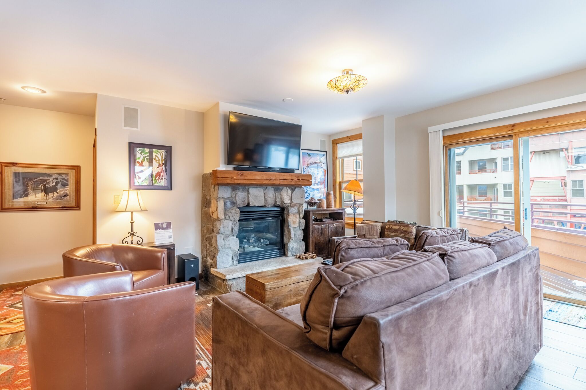 A living room with a stone fireplace, leather sofa, and a large TV.