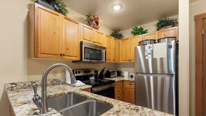 Una cocina con gabinetes de madera, electrodomésticos de acero inoxidable, encimeras de granito y horno empotrado.