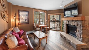 A cozy living room with a leather couch, a wooden table, a fireplace, and a large TV. - Dl8497-2 (Keystone)