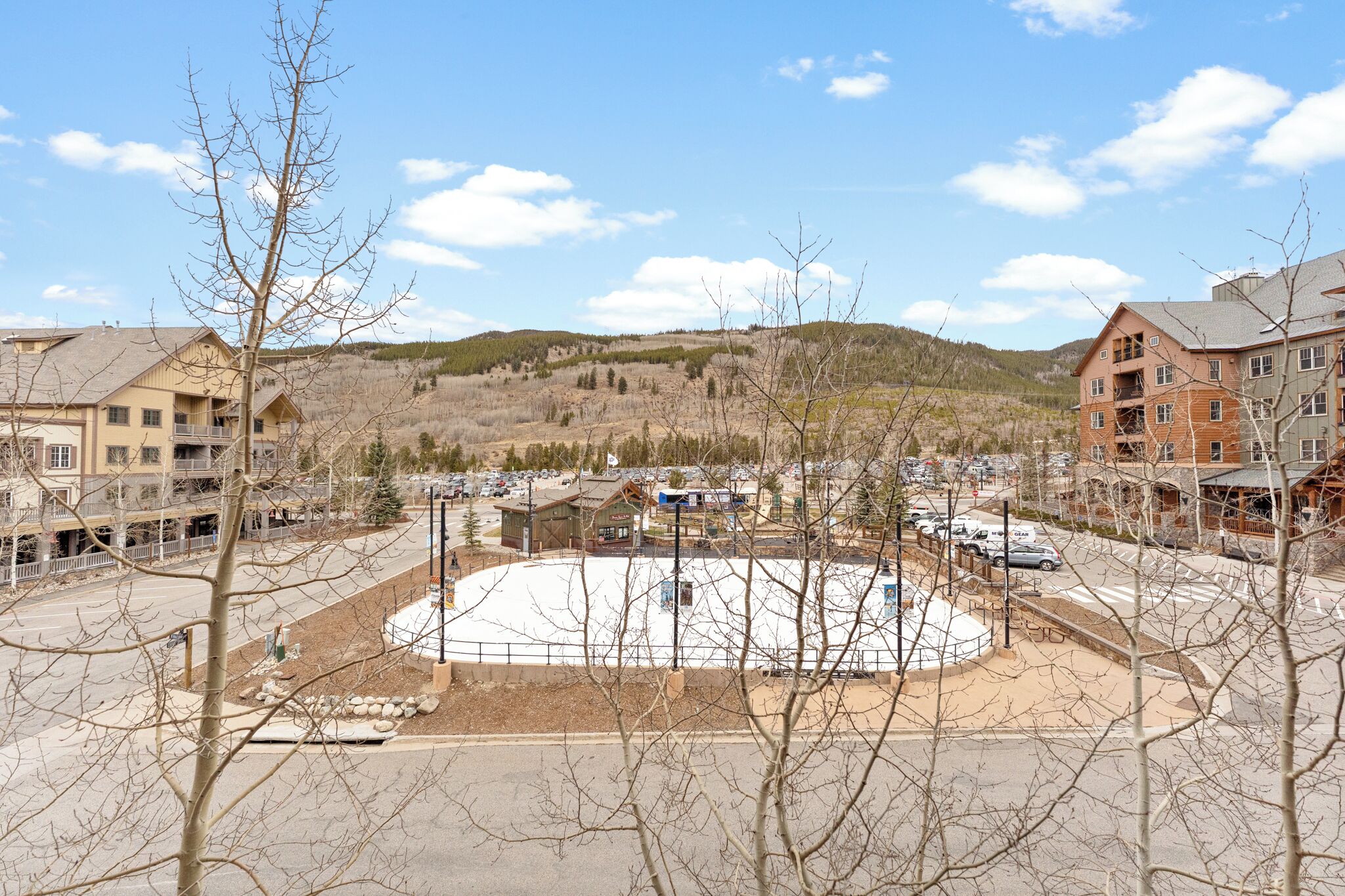 A ski resort with a central plaza, buildings, and a mountainous backdrop.