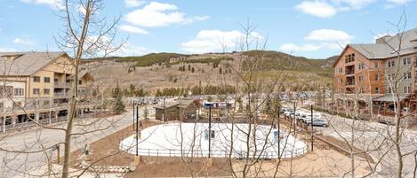 A ski resort with a central plaza, buildings, and a mountainous backdrop.