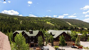 A lodge with multiple buildings, a parking area, and a forested mountain backdrop. - Dakota Lodge #8538 (Keystone)
