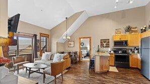 A spacious living area with a loft bedroom, wooden flooring, and a kitchen with modern appliances. - Dakota Lodge #8538 (Keystone)