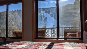 Un dormitori amb una finestra gran que ofereix vistes a un paisatge de muntanya nevada.