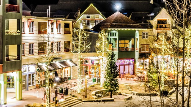 Un pati amb edificis, mobiliari exterior i llums de Nadal.