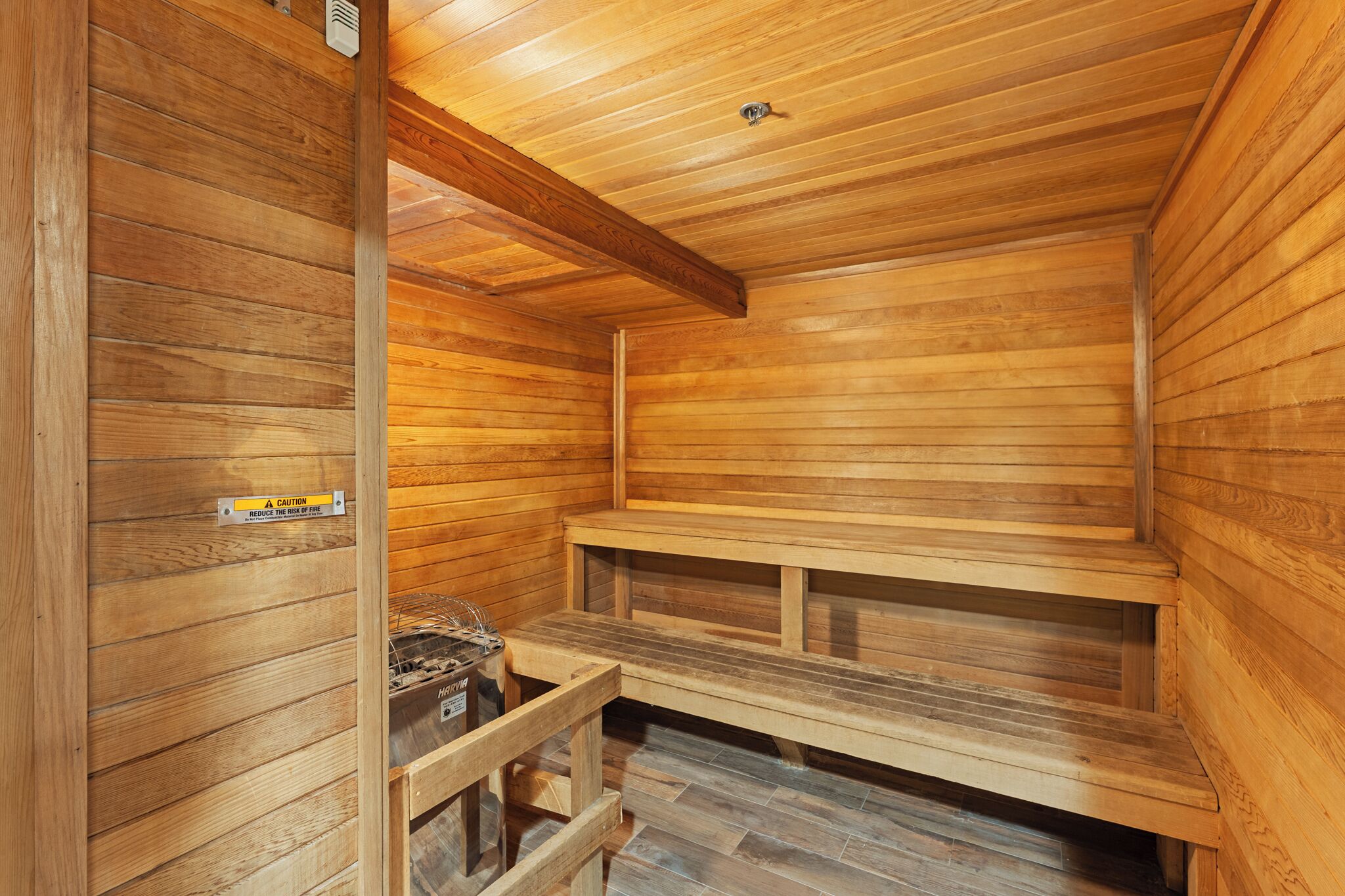 Eine Holzsauna mit Bänken und einem Warnschild.
