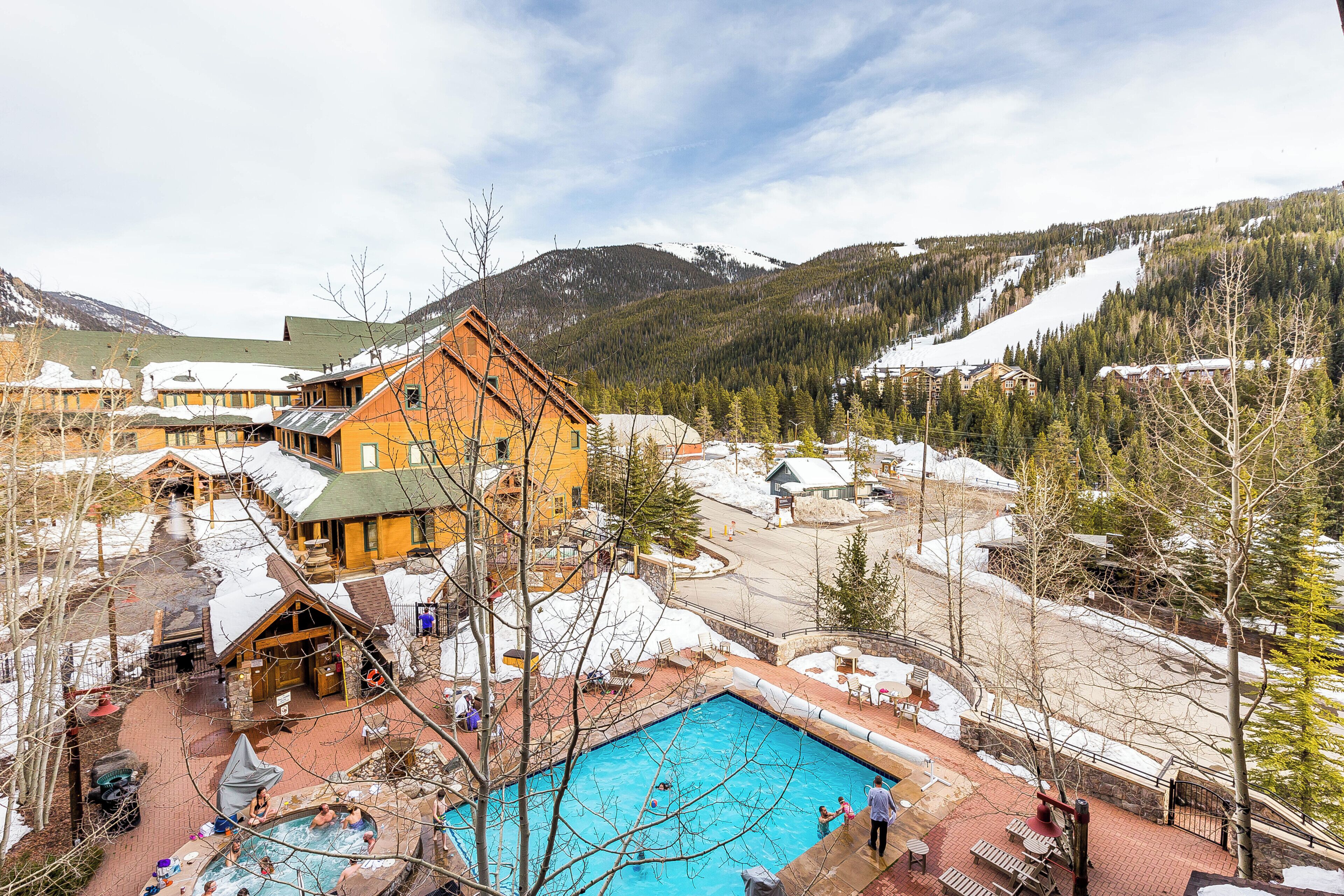 A resort with a swimming pool, outdoor seating, and a mountainous backdrop.