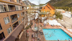 A resort with a pool, wooden buildings, and a mountainous backdrop. - Dl8520-2 (Keystone)