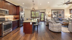 A spacious kitchen with dark wood cabinets, stainless steel appliances, and a central island with bar stools. - A747-4 (Keystone)