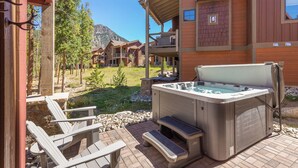 A hot tub and outdoor seating area with a view of a mountain and a building with balconies. - A747-4 (Keystone)