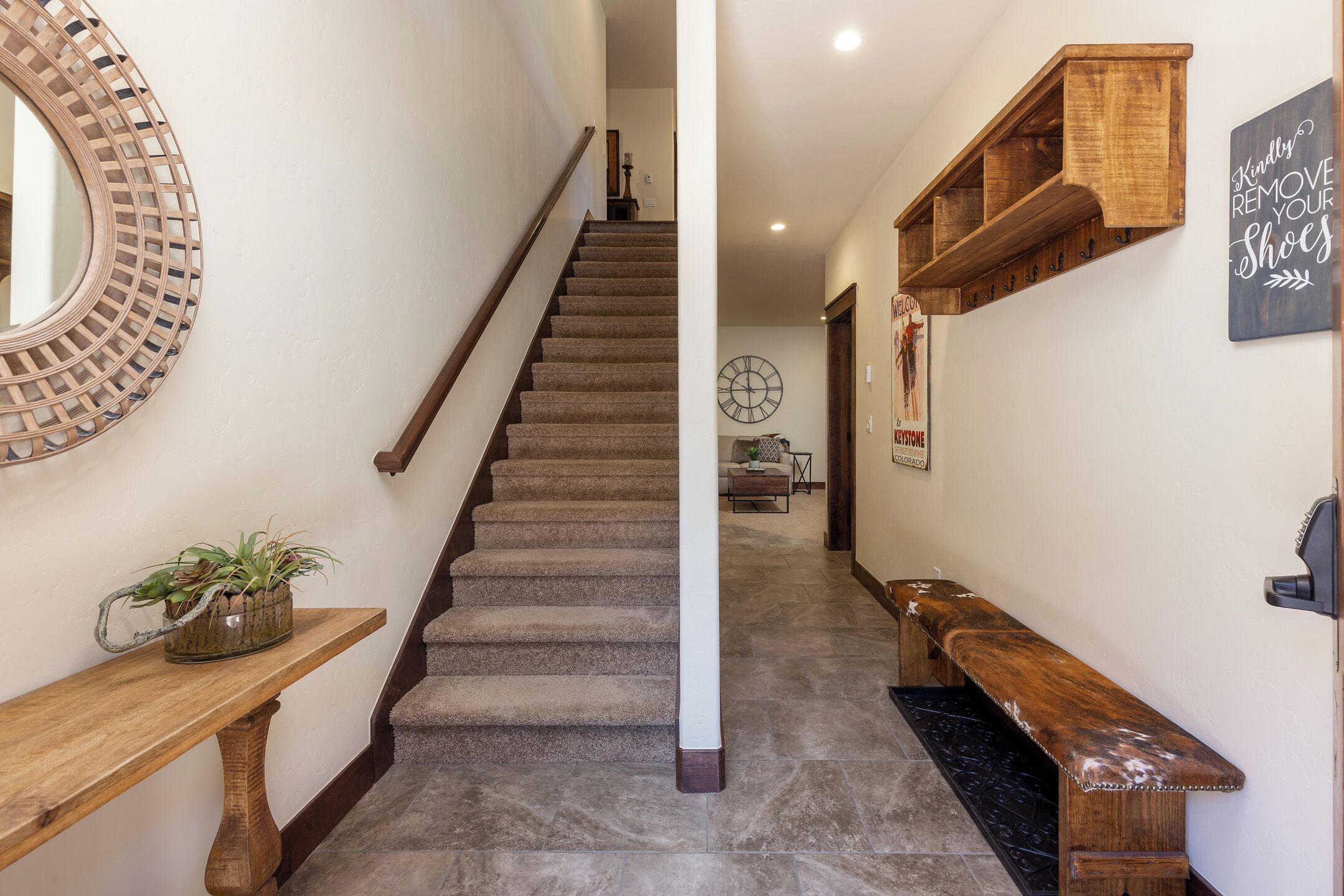 A staircase with a wooden handrail, a potted plant, and a wall-mounted clock.