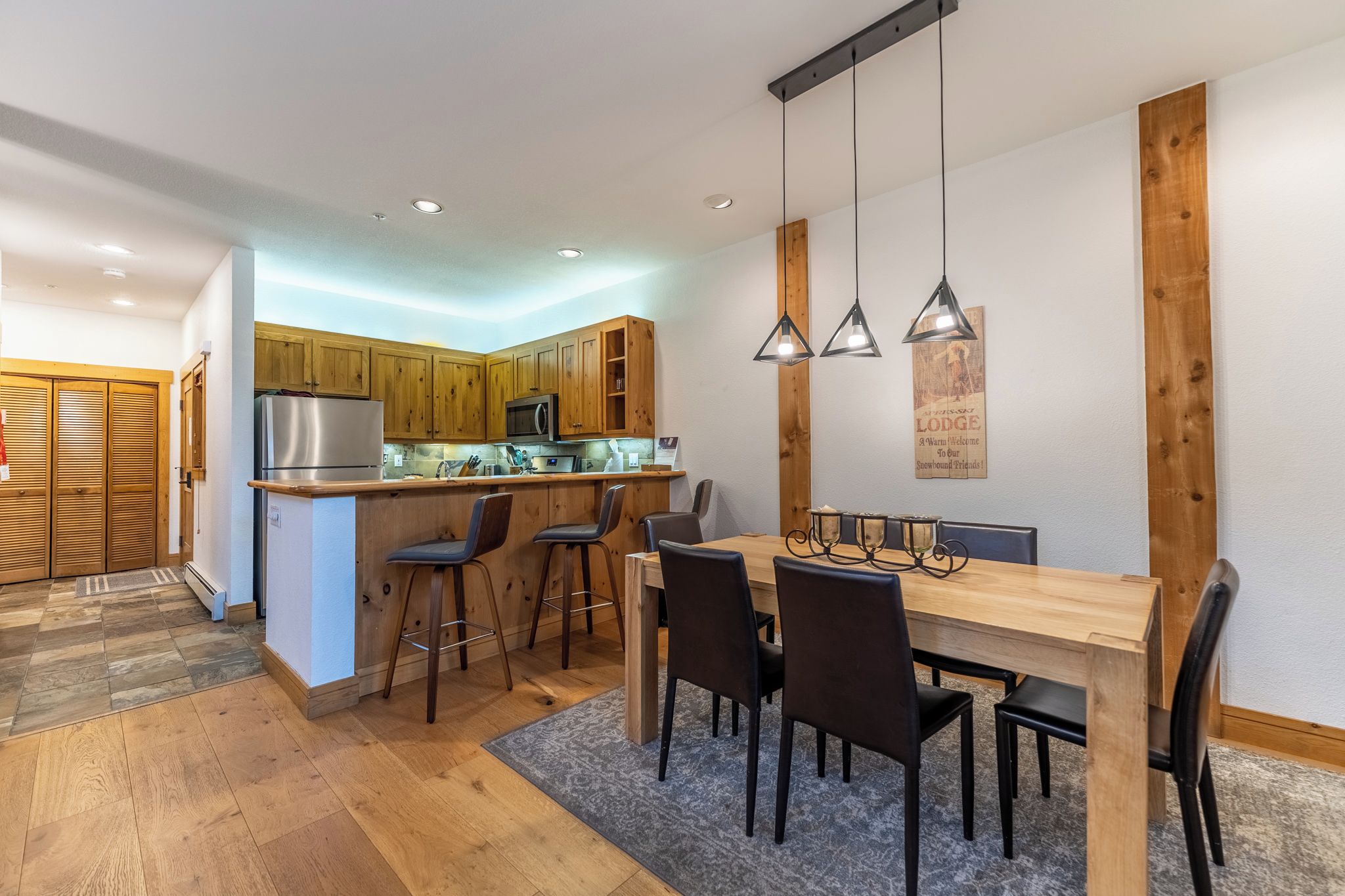 Una cocina moderna con armarios de madera, un refrigerador de acero inoxidable y una zona de bar.