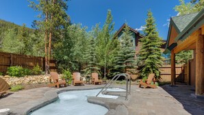 A hot tub area with a wooden deck, surrounded by trees and a wooden fence. - St8715-2 (Keystone)