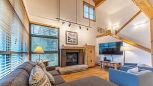A spacious living room with a fireplace, a large TV mounted on the wall, and a cozy seating area with sofas and a blue armchair. - St8715-2 (Keystone)