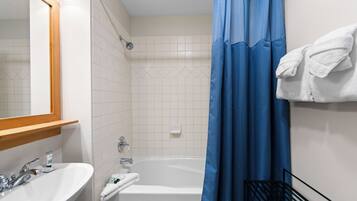 Een badkamer met een witte wastafel, een spiegel, een badkuip en een blauw douchegordijn.