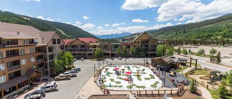 A hotel with multiple floors, a central courtyard with a children's play area, and a mountain backdrop.
