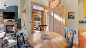 Un rincón comedor acogedor con una mesa y sillas de madera, una chimenea de piedra y un televisor sobre un mueble.