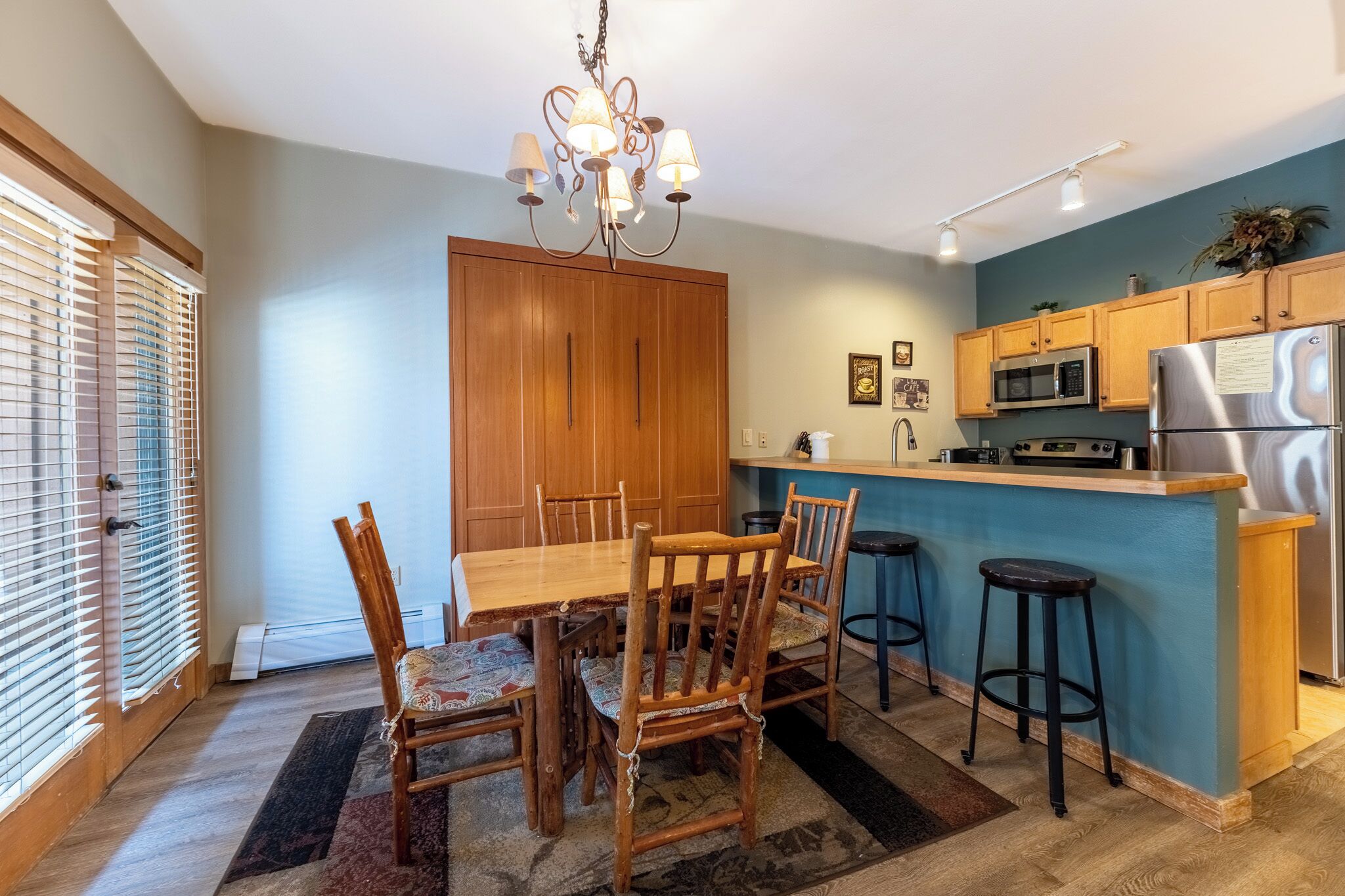 A modern kitchen with wooden cabinets, a stainless steel refrigerator, and a blue accent wall.