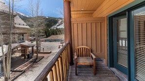 A wooden deck with a chair, a covered area, and a view of a snowy mountain. - Al81101 (Keystone)