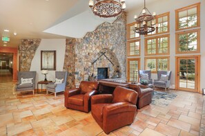 A spacious lobby with a stone fireplace, leather seating, and large windows. - Expedition Station #8599 (Keystone)
