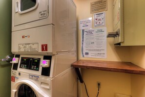 A front-loading washer with a digital display, a wall-mounted dryer, and various instructional signs. - Expedition Station #8599 (Keystone)