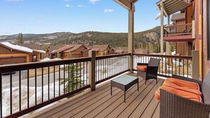 A wooden deck with outdoor furniture, a view of a residential area, and a mountain backdrop. - A39-3 (Keystone)