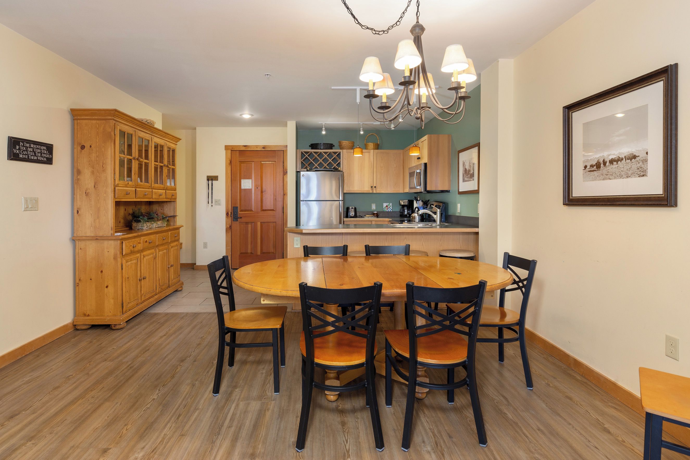 A dining area with a wooden table and chairs, a chandelier, and wooden cabinetry.