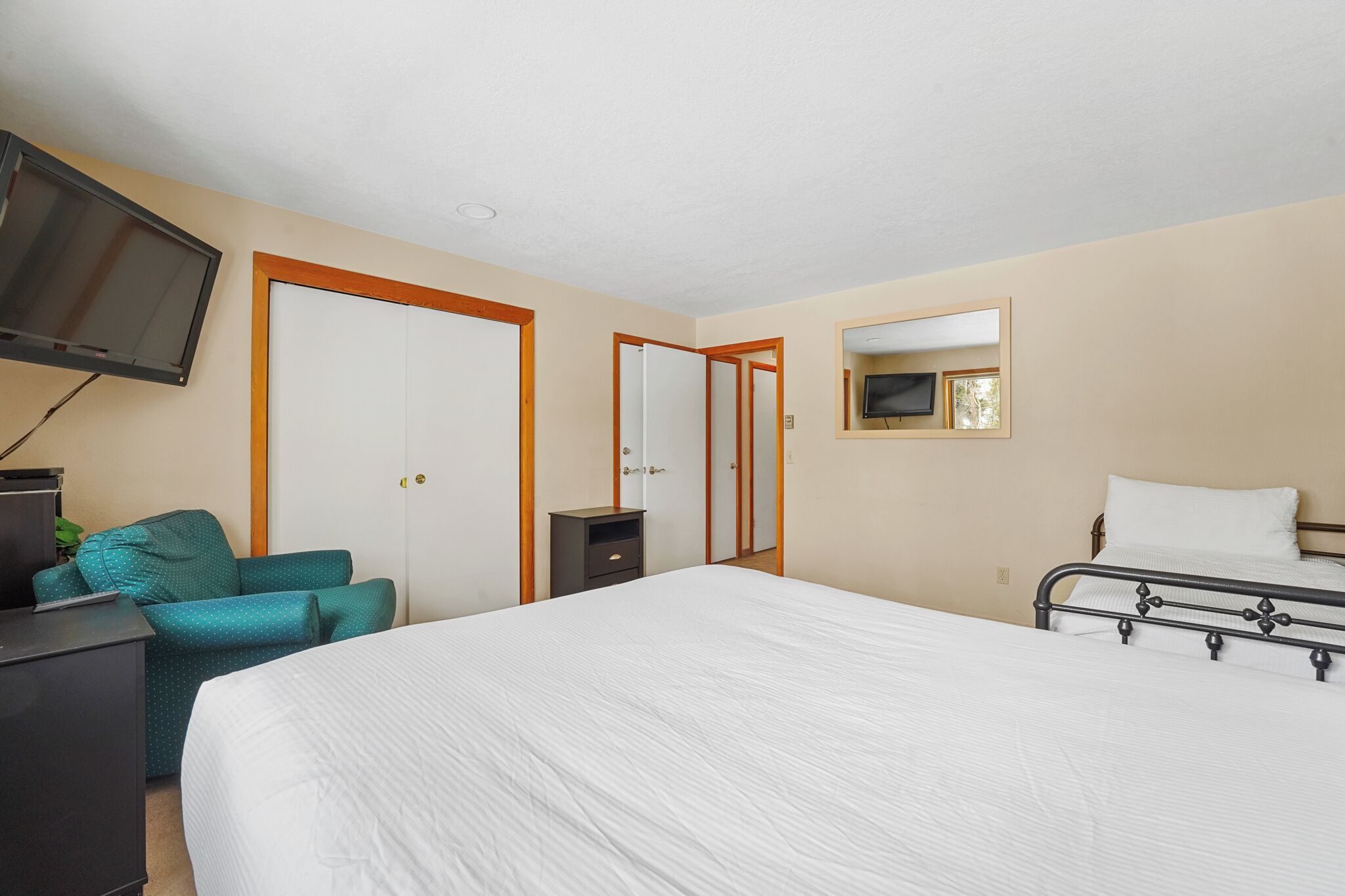 A hotel room with a bed, a desk, a chair, a television, and a wardrobe.