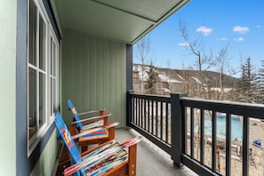 A balcony with skis leaning against the wall, a pool, and a view of buildings and trees. - Expedition Station #8582 (Keystone)