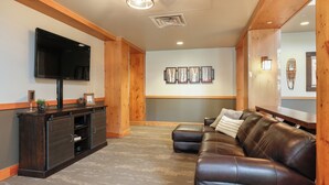A modern living room with a dark wood entertainment unit, a leather sofa, and a flat-screen TV mounted on the wall. - Expedition Station #8582 (Keystone)
