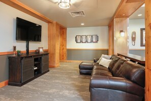 A modern living room with a dark wood entertainment unit, a leather sofa, and a flat-screen TV mounted on the wall. - Expedition Station #8582 (Keystone)
