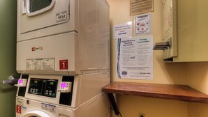 A front-loading washing machine with a digital display, a dryer, and a wooden shelf. - Expedition Station #8582 (Keystone)