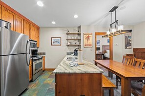 Eine Küche mit Holzausstattung, Edelstahlgeräten, einer Marmorarbeitsplatte und einem Essbereich mit Holztisch und Stühlen.