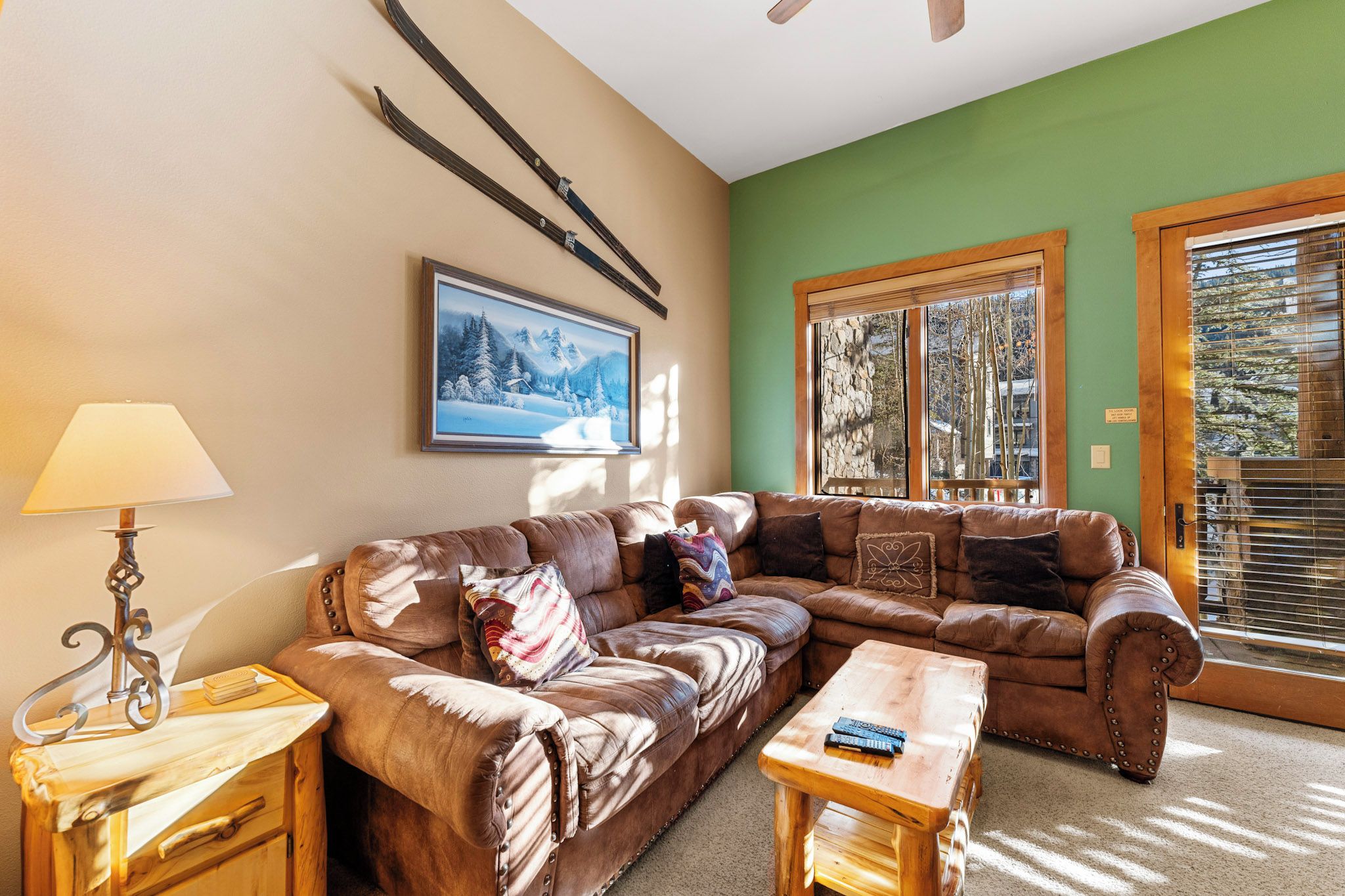 A cozy living room with a brown leather sofa, a wooden coffee table, and a lamp on a side table.