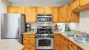 Una cocina con armarios de madera, electrodomésticos de acero inoxidable y encimera de granito.