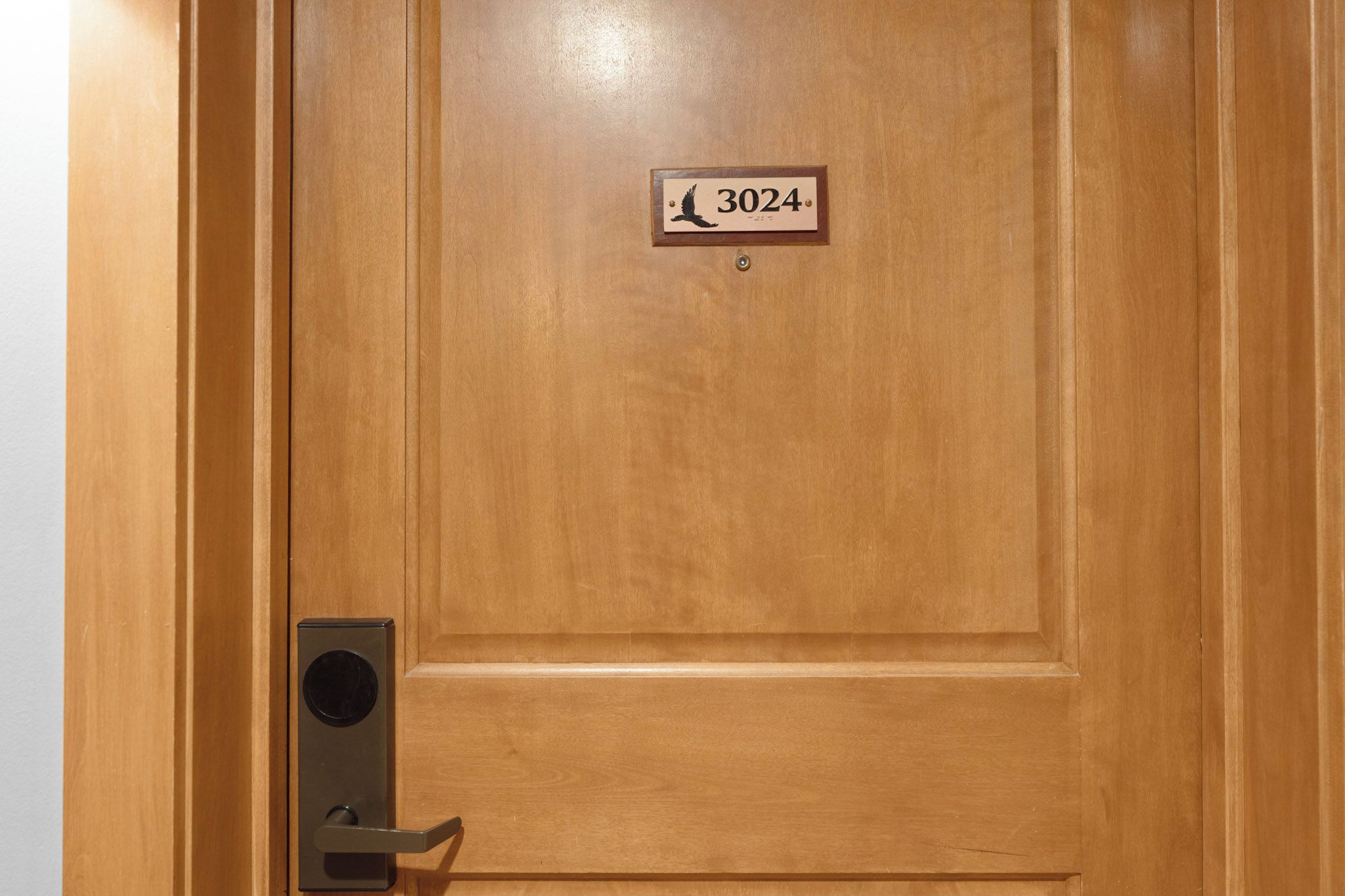 Une porte en bois avec une plaque portant un numéro et un sonnette.