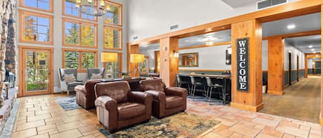 A lobby with a reception desk, leather sofas, a chandelier, and large windows.