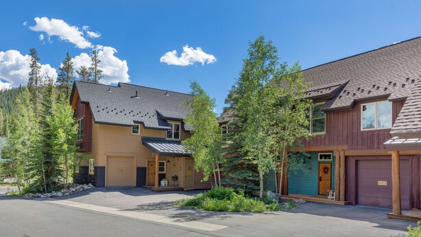 A residential area with two houses, each with a garage, surrounded by trees and a clear sky. - Ski Tip #8719 : 2 (Keystone)