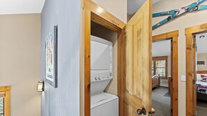 A laundry room with a white washer and dryer, wooden doors, and a ski-themed poster on the wall. - Ski Tip #8719 : 2 (Keystone)