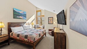 A bedroom with a wooden bed, a TV, a desk, and a window with a view of a mountain landscape. - Ski Tip #8719 : 2 (Keystone)